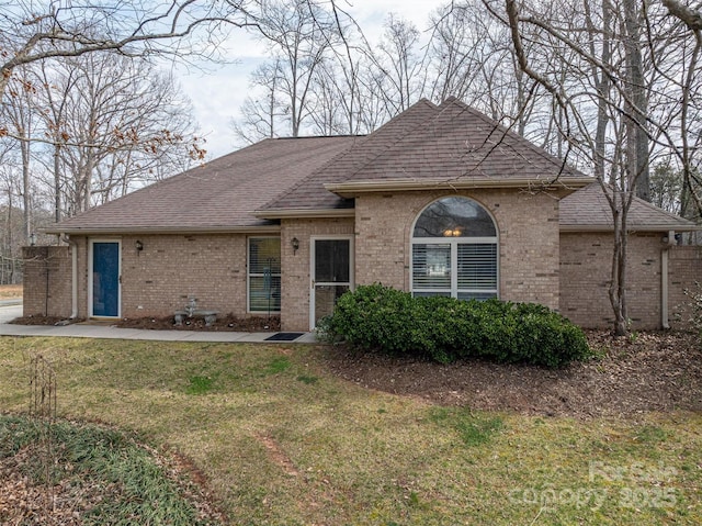 ranch-style house featuring roof with shingles, a front lawn, and brick siding