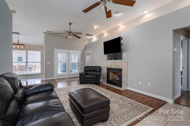 living room with a tile fireplace, recessed lighting, wood finished floors, visible vents, and baseboards