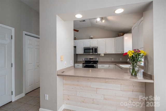 kitchen with light tile patterned floors, stainless steel appliances, visible vents, white cabinets, and vaulted ceiling