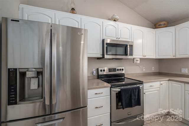 kitchen featuring white cabinets, lofted ceiling, light countertops, stainless steel appliances, and a textured ceiling