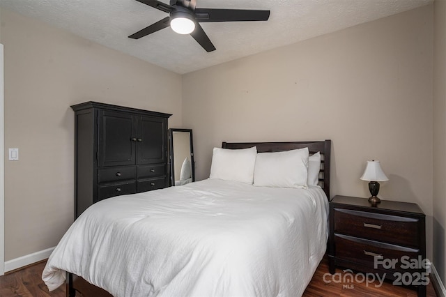 bedroom featuring dark wood-style floors, ceiling fan, baseboards, and a textured ceiling