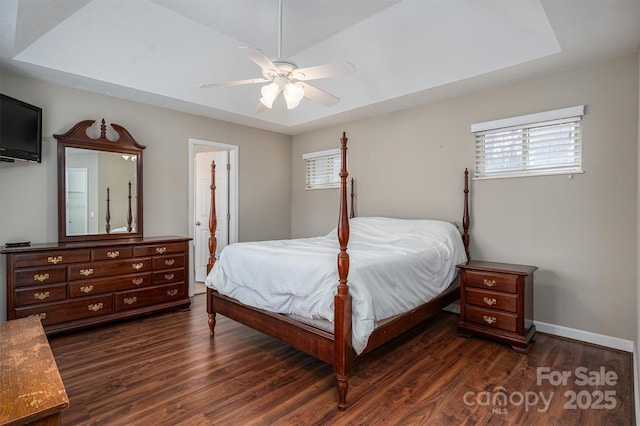 bedroom featuring ceiling fan, baseboards, a raised ceiling, and dark wood finished floors