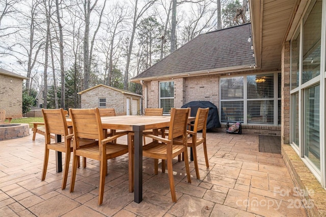 view of patio featuring an outbuilding, outdoor dining space, and a fire pit