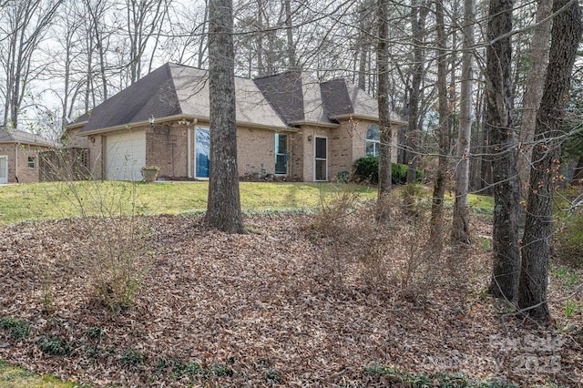 view of front of house featuring brick siding, a front lawn, an attached garage, and a shingled roof