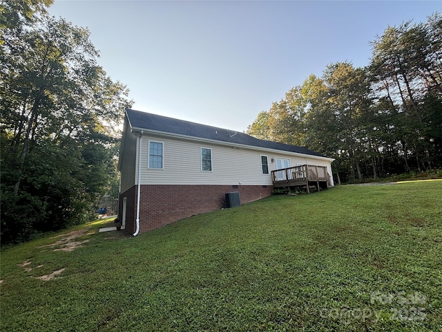 view of property exterior featuring a wooden deck, central AC, and a lawn