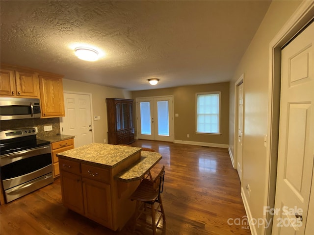 kitchen featuring french doors, stainless steel appliances, dark hardwood / wood-style floors, and a kitchen island