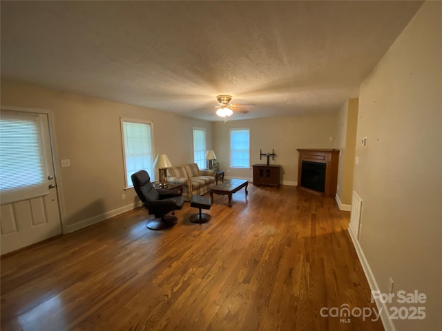 unfurnished living room featuring ceiling fan, a textured ceiling, and dark hardwood / wood-style flooring