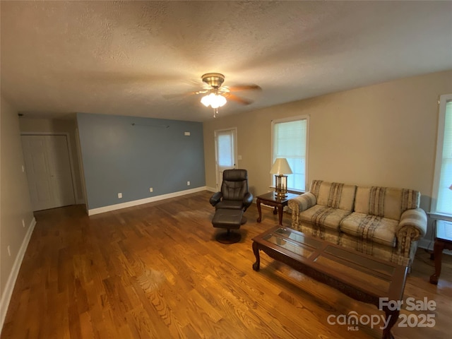 living room with hardwood / wood-style flooring, ceiling fan, and a textured ceiling