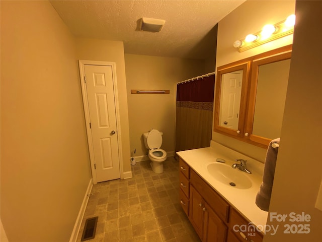 bathroom featuring walk in shower, vanity, toilet, and a textured ceiling