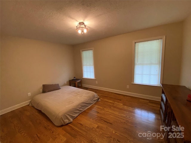 bedroom featuring a textured ceiling and dark hardwood / wood-style flooring