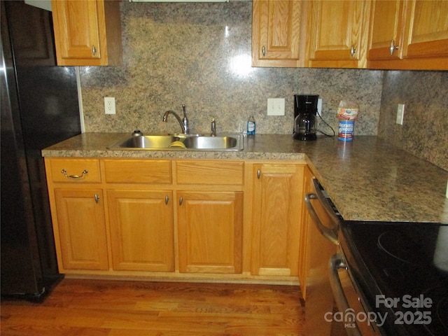 kitchen with stainless steel appliances, tasteful backsplash, sink, and light wood-type flooring