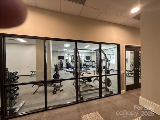 exercise room featuring a towering ceiling, a drop ceiling, and french doors