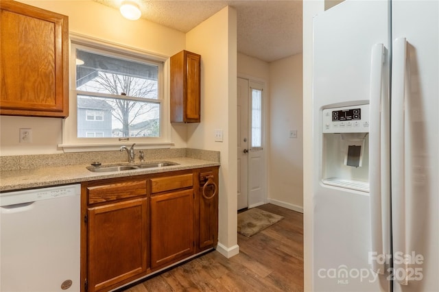 kitchen with sink, white appliances, light hardwood / wood-style floors, and a textured ceiling