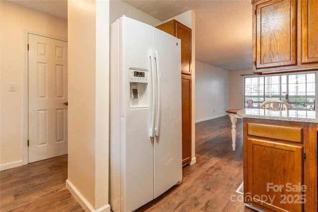 kitchen with white fridge with ice dispenser and light hardwood / wood-style floors