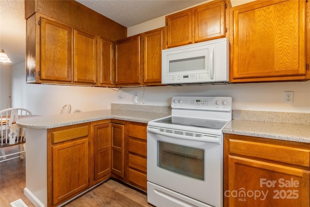 kitchen with light stone counters, white appliances, light hardwood / wood-style floors, and a textured ceiling