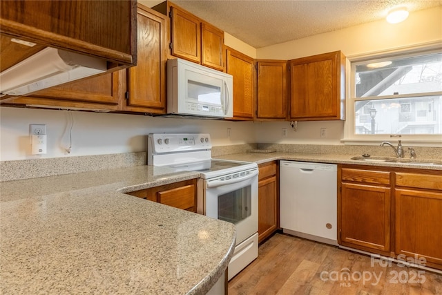 kitchen with sink, white appliances, light stone counters, a textured ceiling, and light wood-type flooring