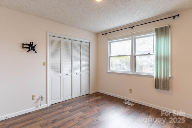 unfurnished bedroom featuring dark hardwood / wood-style floors, a textured ceiling, and a closet