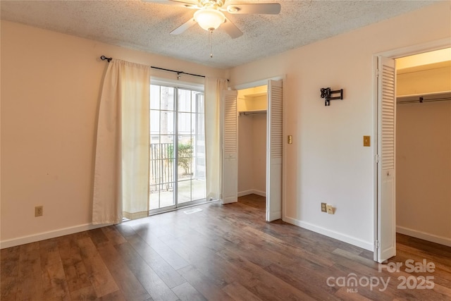 unfurnished bedroom with multiple closets, ceiling fan, a textured ceiling, and dark hardwood / wood-style flooring