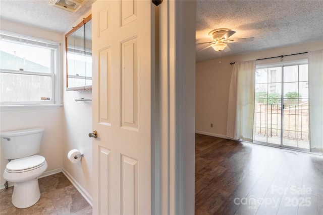 bathroom featuring hardwood / wood-style flooring, ceiling fan, toilet, and a textured ceiling