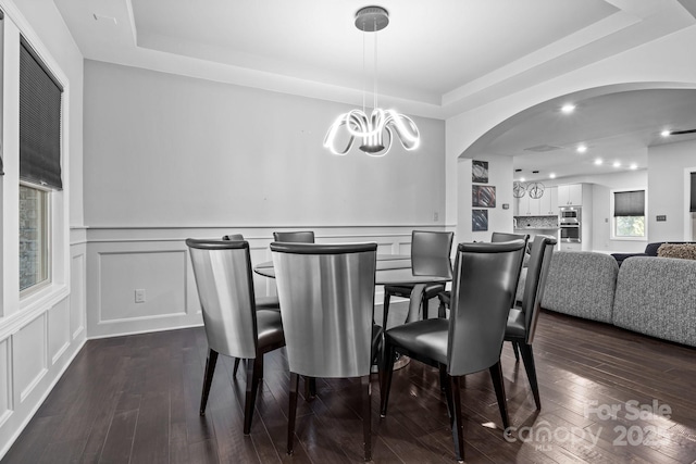 dining room featuring a tray ceiling, dark hardwood / wood-style floors, and a chandelier