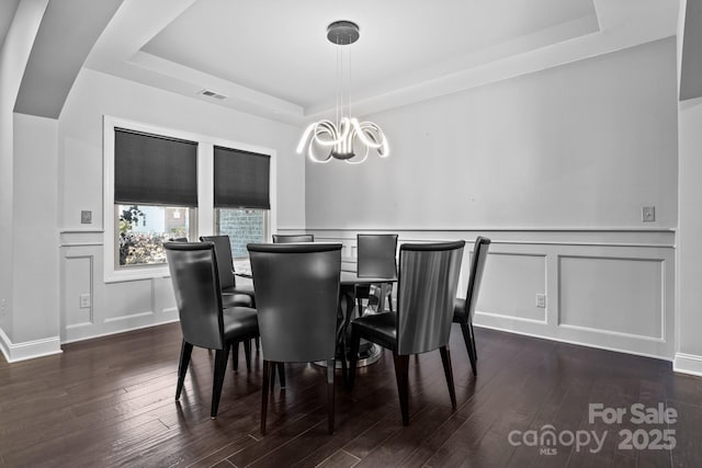 dining area featuring a notable chandelier, dark hardwood / wood-style flooring, and a tray ceiling