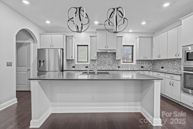 kitchen with hanging light fixtures, white cabinetry, appliances with stainless steel finishes, and a kitchen island with sink