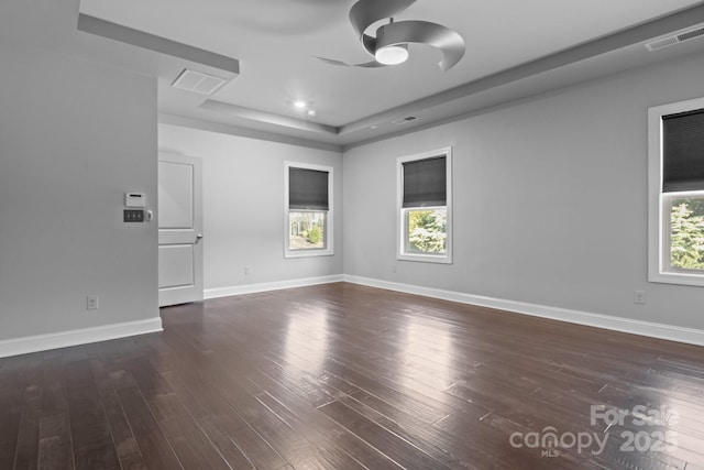 unfurnished room with a raised ceiling, dark wood-type flooring, and ceiling fan