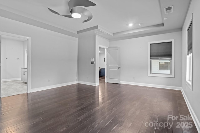 spare room featuring dark hardwood / wood-style flooring, a tray ceiling, and ceiling fan