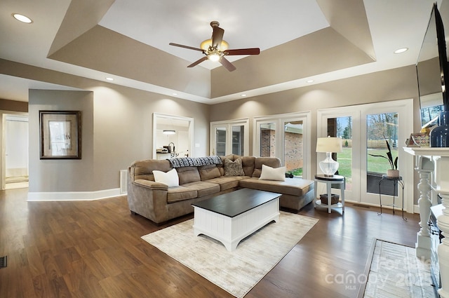 living room with ceiling fan, a tray ceiling, dark hardwood / wood-style flooring, and a high ceiling