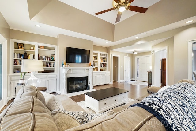 living room with ceiling fan, built in features, and light wood-type flooring