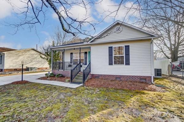 bungalow-style house featuring central AC unit, covered porch, and a front yard