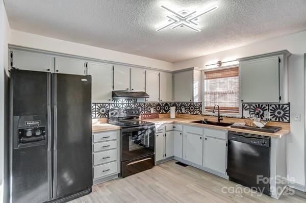 kitchen with tasteful backsplash, sink, light hardwood / wood-style flooring, and black appliances