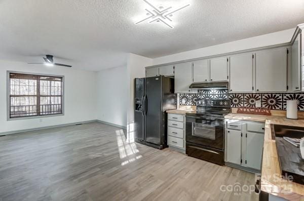 kitchen featuring gray cabinets, decorative backsplash, light hardwood / wood-style floors, and black appliances