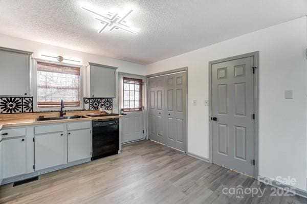 kitchen with dishwasher, sink, backsplash, a textured ceiling, and light hardwood / wood-style flooring