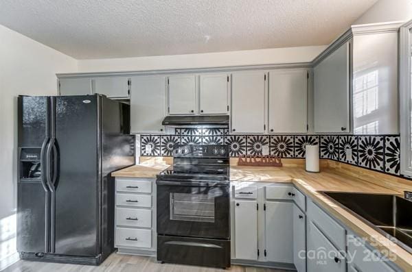 kitchen with gray cabinetry, black appliances, light hardwood / wood-style floors, a textured ceiling, and decorative backsplash