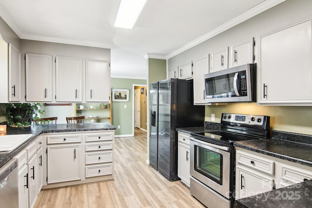 kitchen with crown molding, white cabinetry, dark stone countertops, stainless steel appliances, and light hardwood / wood-style floors