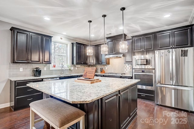 kitchen featuring sink, hanging light fixtures, a center island, stainless steel appliances, and dark wood-type flooring