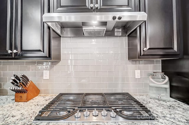 kitchen featuring ventilation hood, tasteful backsplash, light stone countertops, and stainless steel gas cooktop