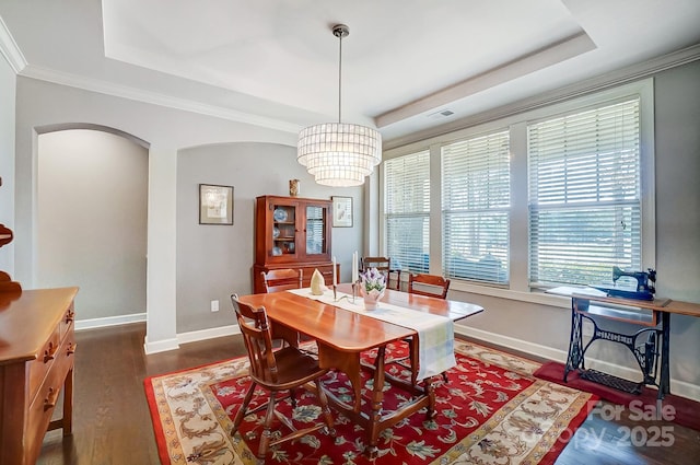 dining space featuring a raised ceiling, ornamental molding, dark hardwood / wood-style floors, and a notable chandelier