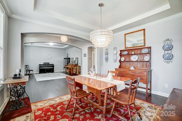 dining space with an inviting chandelier, crown molding, dark wood-type flooring, and a raised ceiling