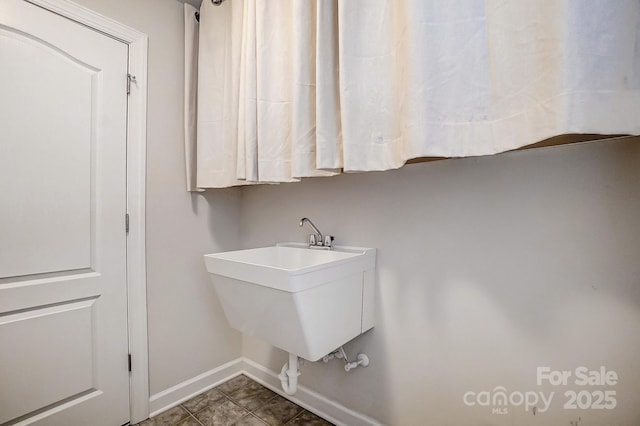 clothes washing area featuring sink and dark tile patterned flooring