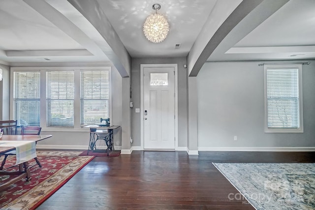 foyer with a tray ceiling, dark hardwood / wood-style flooring, and a notable chandelier