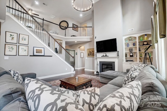 living room with a towering ceiling, wood-type flooring, and a notable chandelier