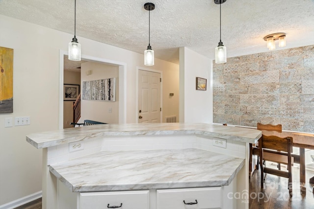 kitchen with white cabinetry, hanging light fixtures, and a textured ceiling