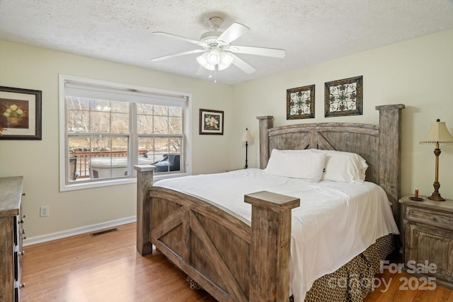 bedroom with ceiling fan, light hardwood / wood-style floors, and a textured ceiling