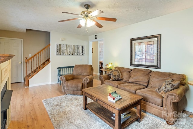 living room with ceiling fan, light hardwood / wood-style flooring, and a textured ceiling