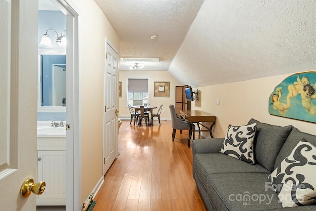 living room with hardwood / wood-style floors, vaulted ceiling, sink, and a textured ceiling