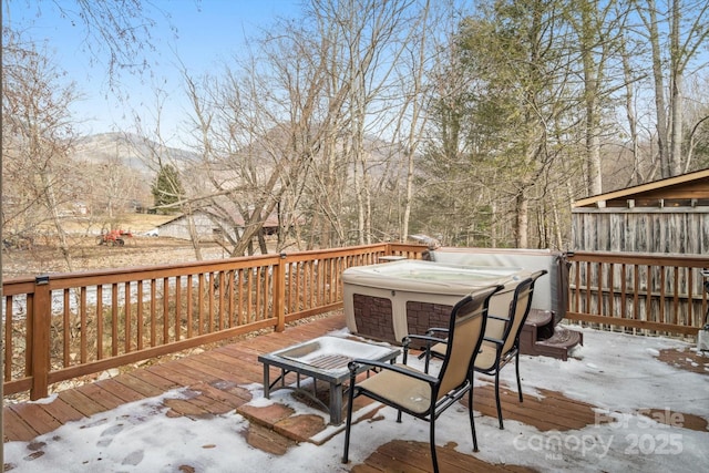 snow covered deck with a mountain view and a hot tub