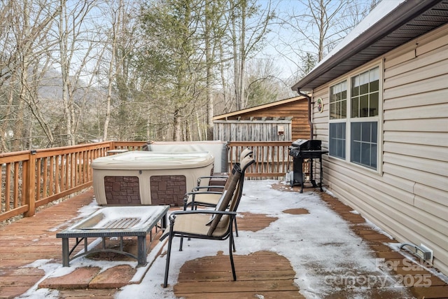 snow covered deck with area for grilling and a hot tub