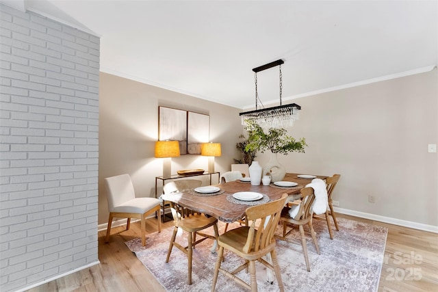 dining area with crown molding, brick wall, and light hardwood / wood-style floors